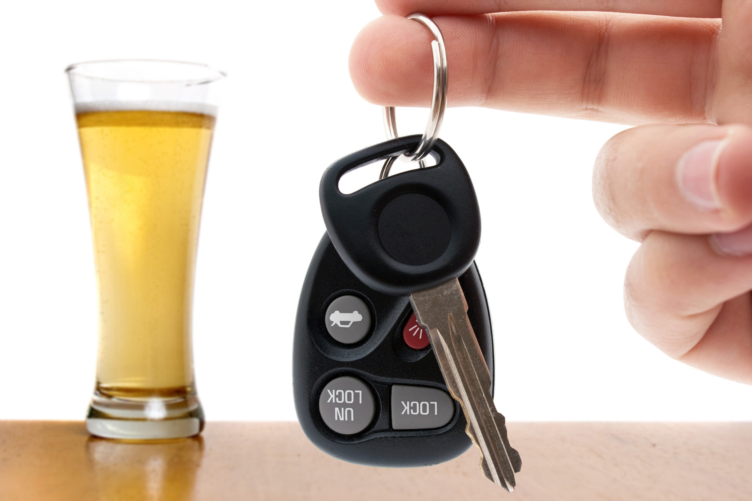 drunk driving conceptual image with a hand holding some car keys and a glass of beer in the background shallow depth of field_SF9e_o_0Bo scaled