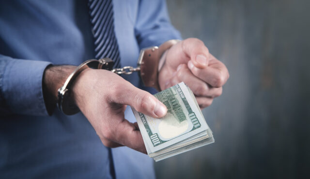 DUI money cost man handcuffed with money in hand