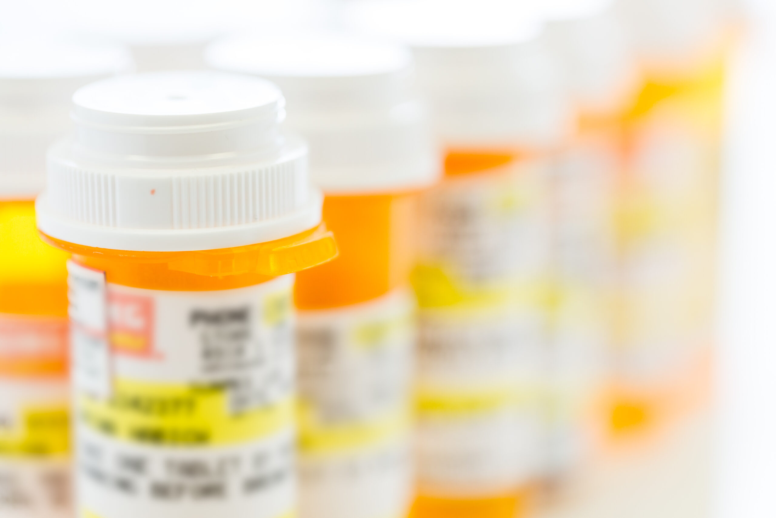 Prescription pills in yellow bottles on a white background