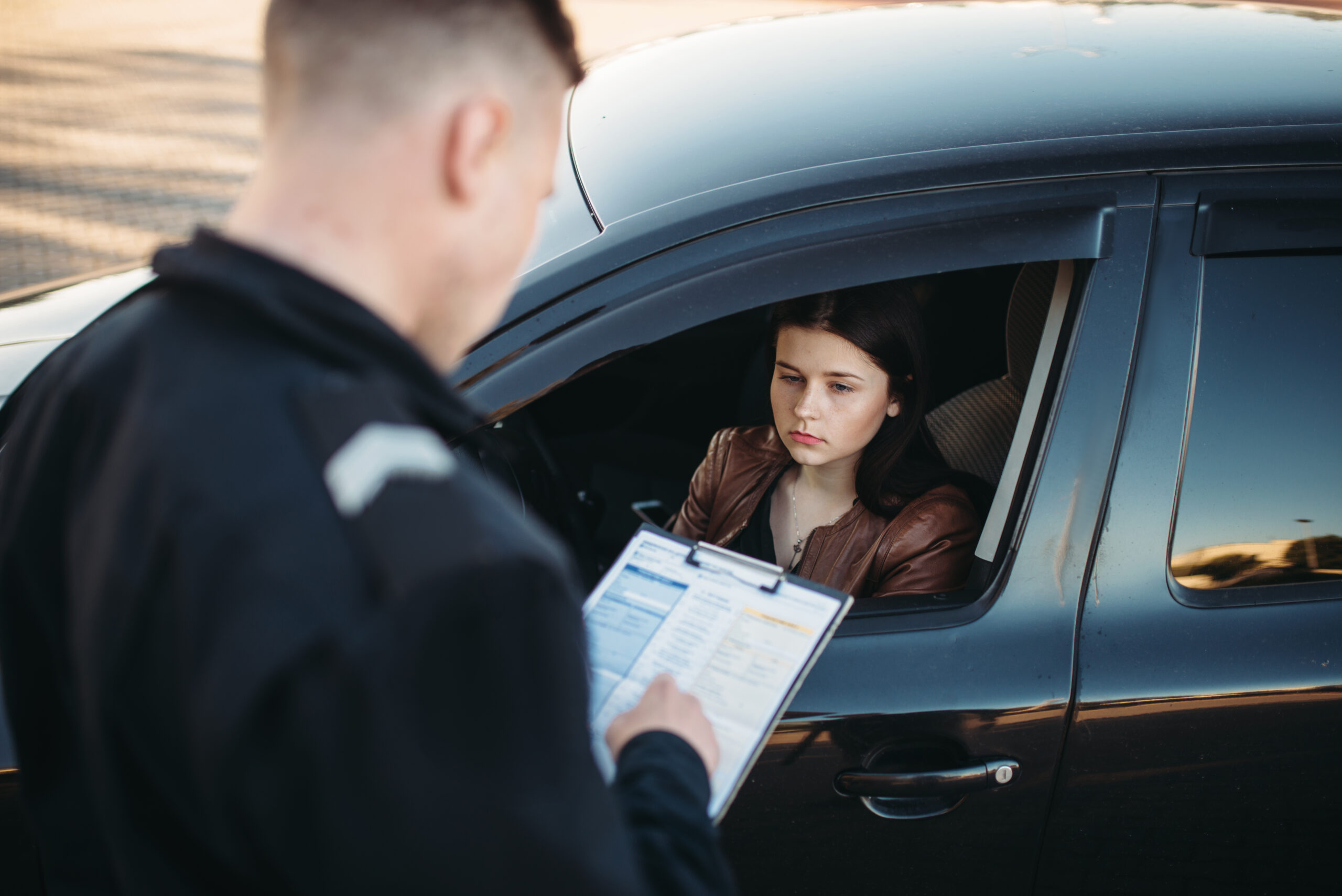 Policeman in uniform writes a fine to female driver. Law protection, car traffic inspector, safety control job