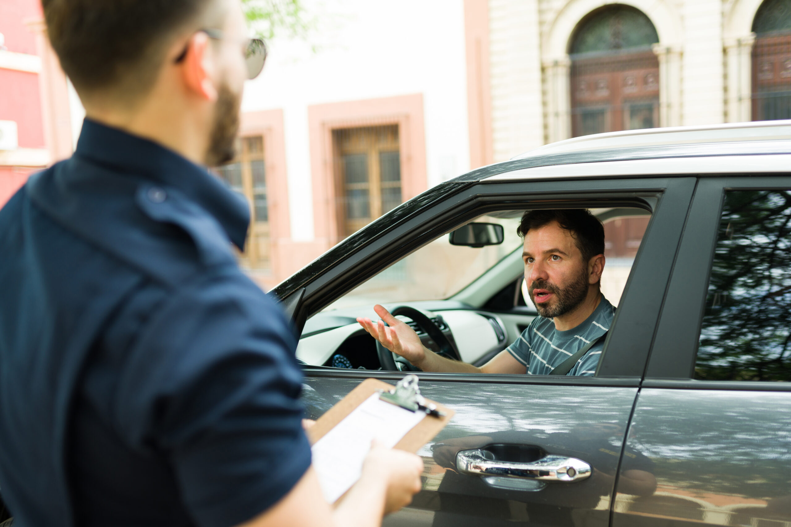 Upset angry man driver arguing with a police officer because of his traffic fine while driving