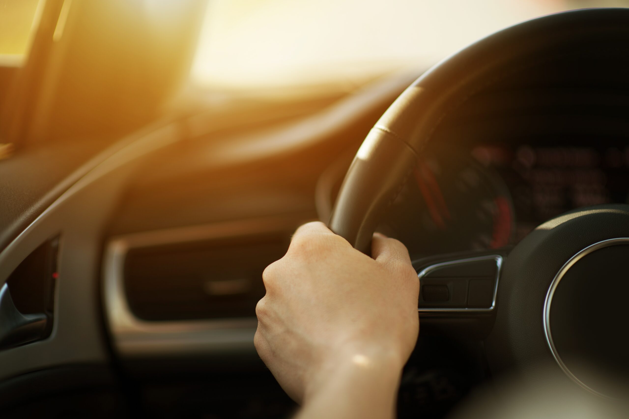 motorist hand on wheel driving sun shining through windshield