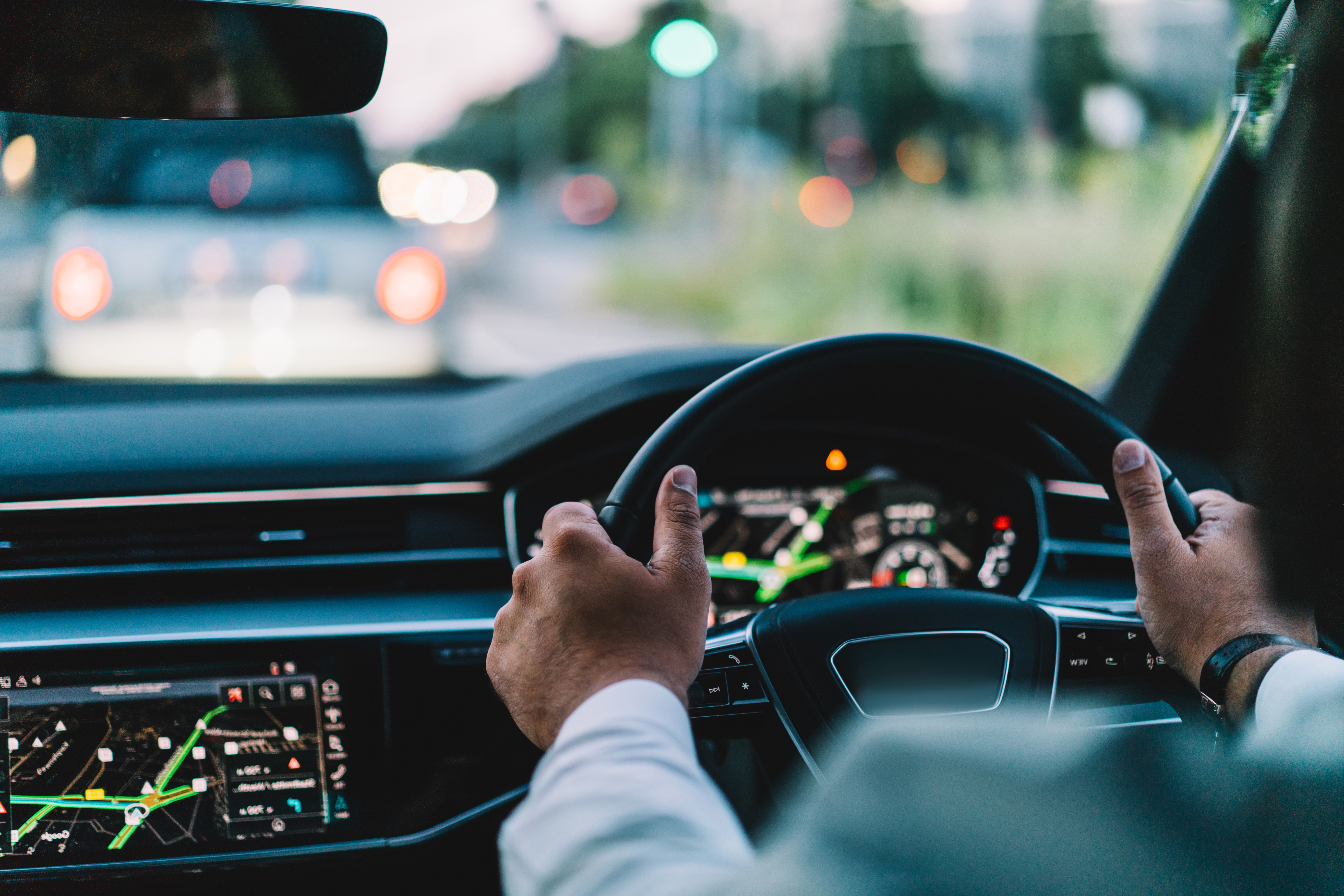 Back cropped view of automobile wheel and male enjoying roadway in contemporary motorized transport for travel, selective focus on autonomous head up during destination driving in comfortable car