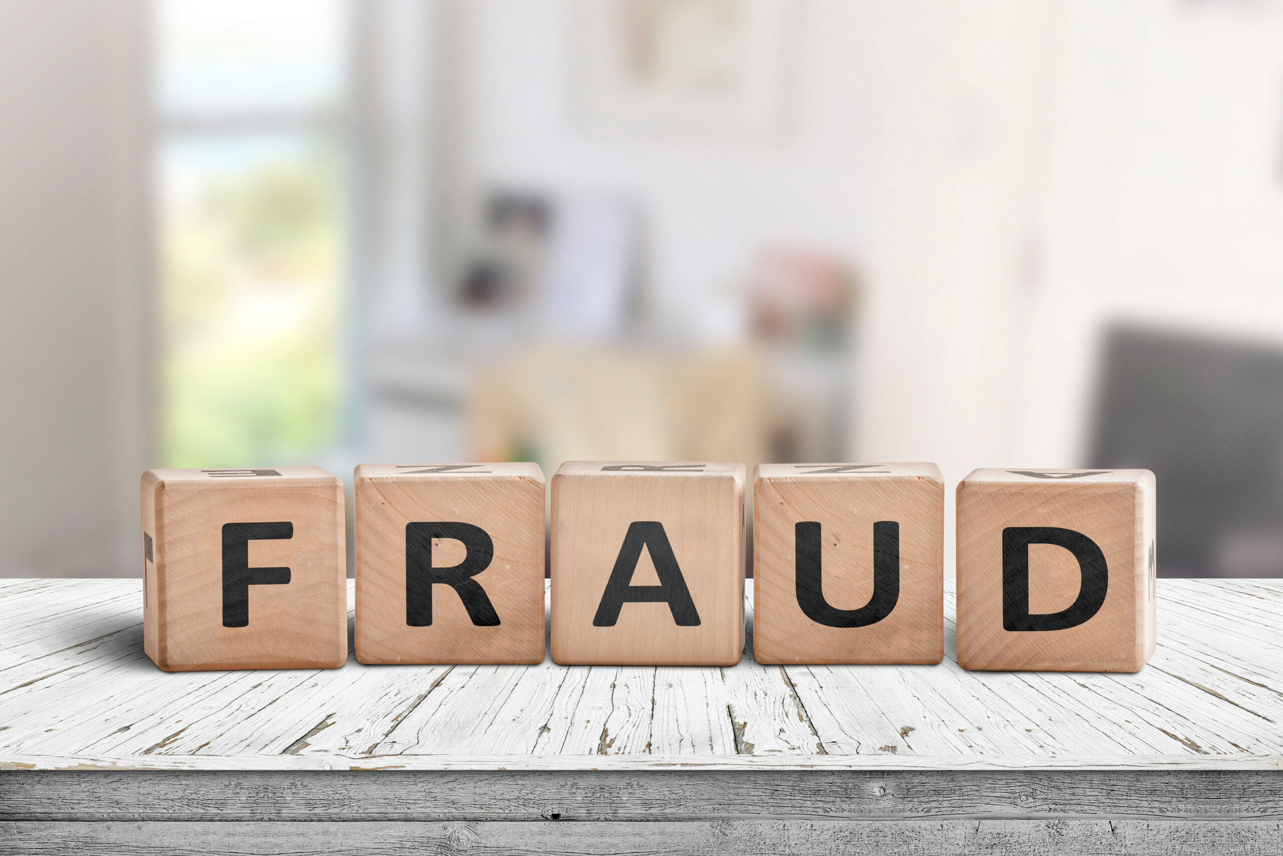 Fraud sign made of wooden blocks on a white desk