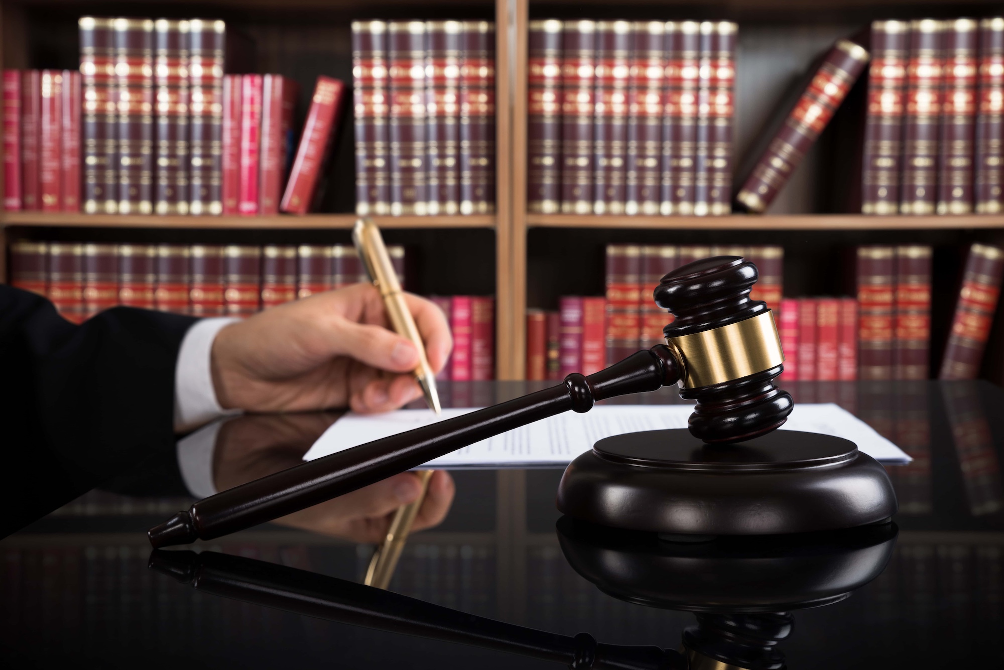 Close up Of Judge Writing On Paper And Gavel At Desk