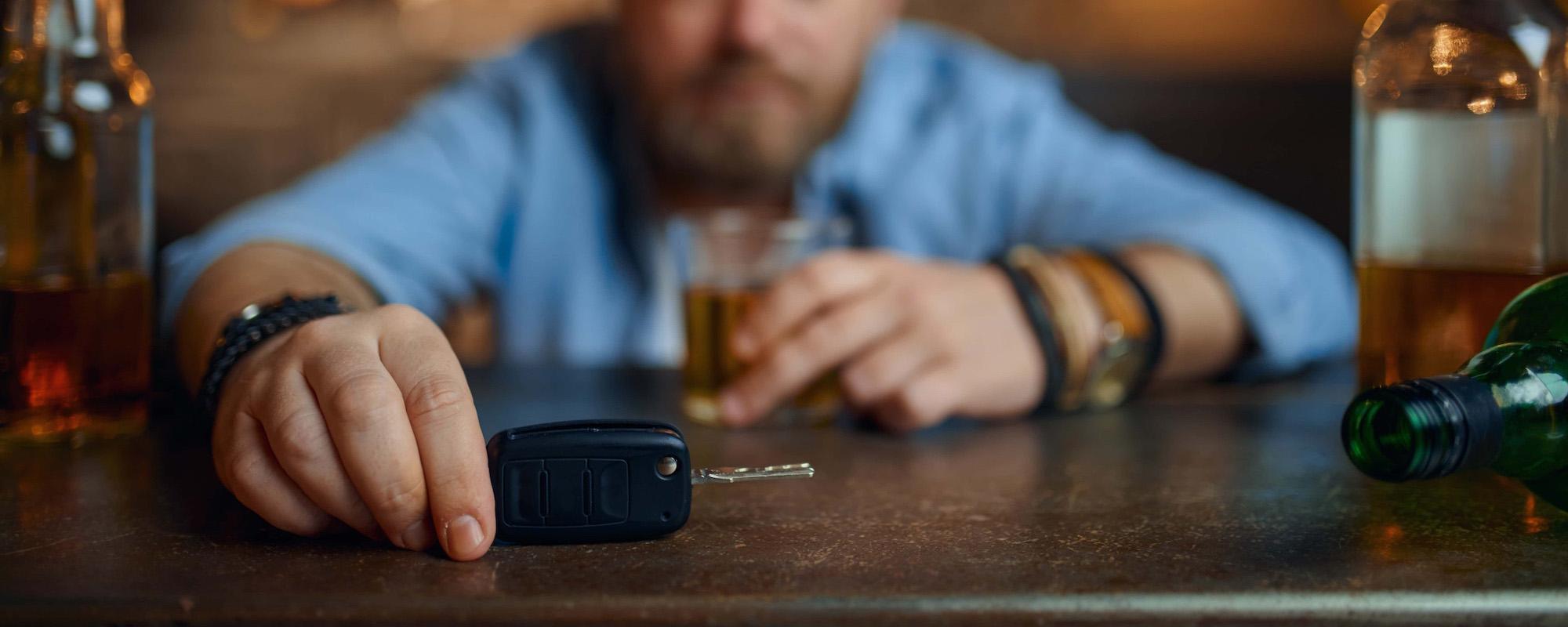Drunk man with car key sitting at counter in bar