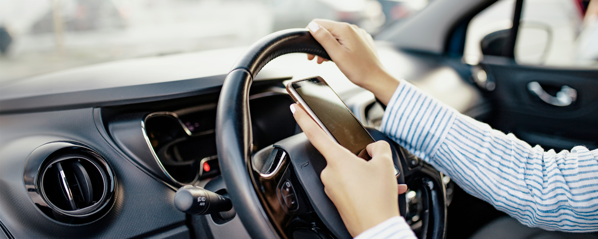 Young woman holding blank screen cell phone driving car