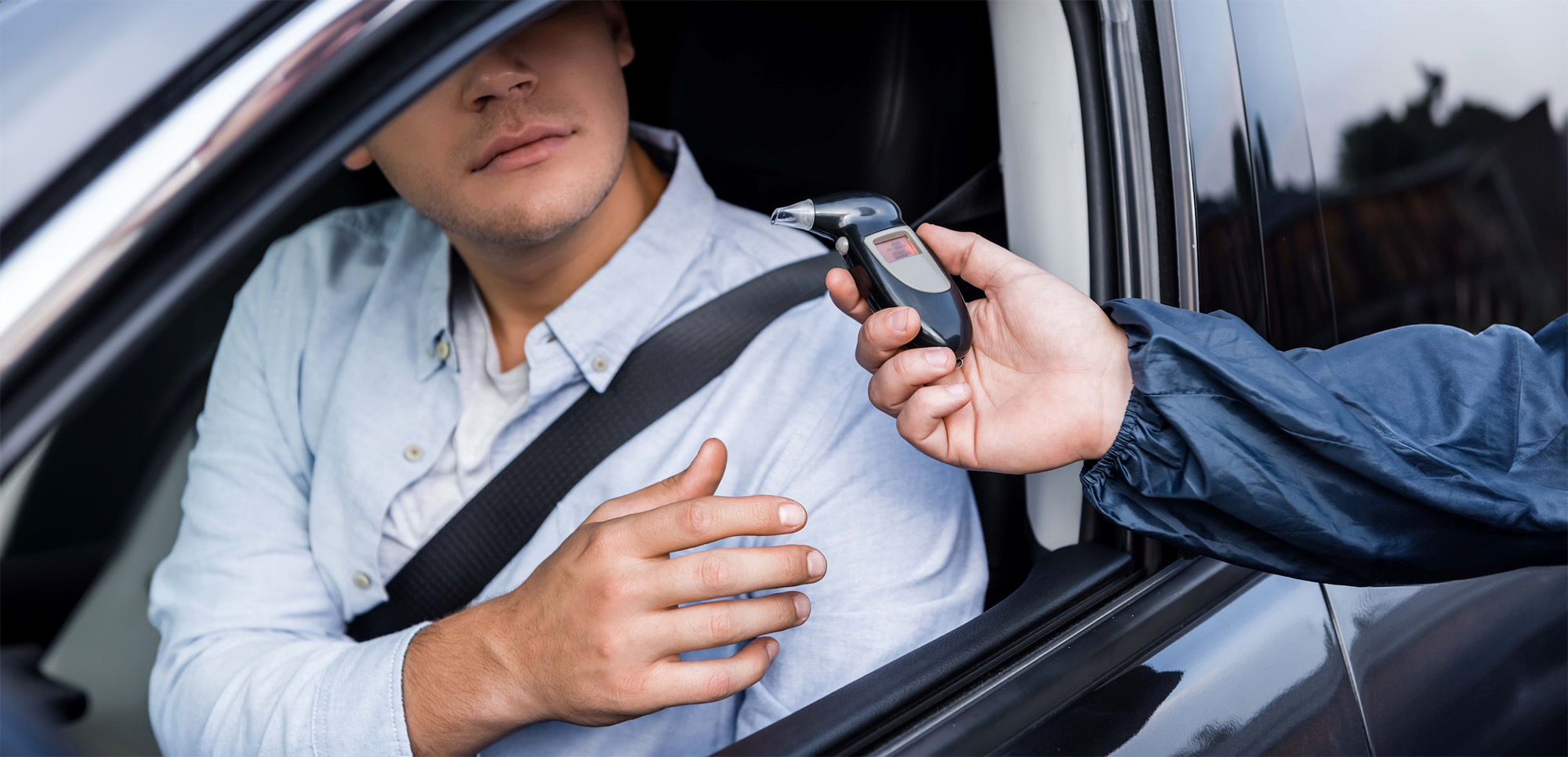 cropped view of driver taking breathalyzer from policeman while sitting in car