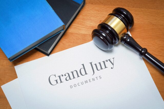 Grand Jury. Document with label. Desk with books and judges gavel in a lawyer's office.